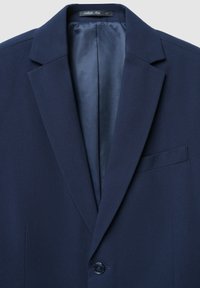 Blazer blu navy con revers a punta, chiusura a un bottone e taschino sul petto. Fodera interna liscia di un tono più chiaro.