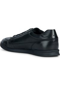 Černé kožené tenisky s hladkým povrchem, nízkým profilem a zaoblenou špičkou. Mají tonální tkaničky a měkkou vnitřní podšívku. Zpevněné švy jako akcenty.