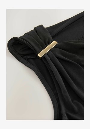 Must mustrihm, millel on kokku kogutud kangas ühel õlal, millel on ristkülikukujuline kuldne metalldetail. Pehme tekstuur ja ülisujuv disain.