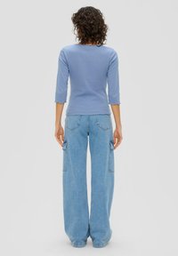 Lichtblauw geribbeld topje met driekwartmouwen, gecombineerd met lichtblauwe denim cargo broek met wijde pijpen, voorzien van zijzakken en een ontspannen pasvorm.