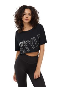 T-shirt nera corta realizzata in tessuto morbido, con una stampa audace in bianco con la scritta "STYLE" decorata con un motivo leopardato. Abbinata a leggings neri a vita alta.