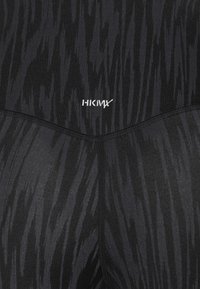 Czarne legginsy sportowe z teksturowanym, falistym wzorem. Z białym logo HKMX. Miękki, elastyczny materiał o dopasowanym kroju.