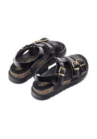 Zwarte leren sandalen met een ontwerp van drie banden, gouden gespen en een textuur van kurken voetbed. Dikke zwarte zool voor extra hoogte.