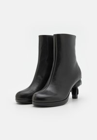 Sorte lær ankle støvler med et slankt design og rund tå, som har en unik blokkehæle for stabilitet. Glat tekstur og minimalistisk stil.