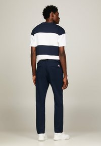 Camicetta a righe navy e bianche a maniche corte abbinata a pantaloni navy. Scarpe bianche, design minimalista, senza modelli o hardware visibili.