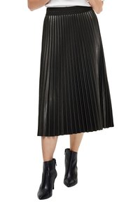 Falda negra plisada con un acabado texturizado, que presenta una ancha cinturilla elástica y cae a la mitad de la pantorrilla, combinada con botas negras hasta el tobillo.