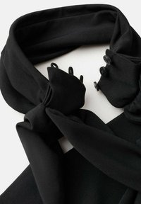 Čierny šál z hladkej látky, s uzlovým dizajnom a gombíkmi na jednej strane. Materiál má mierny lesk; textúra pôsobí mäkko.