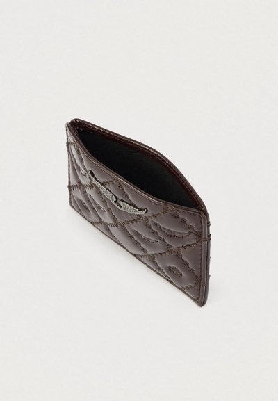 Κασσίτερος κάρτας από καφέ δέρμα με υφή καπιτονέ και ασημένια λεπτομέρεια. Άνοιγμα στο πλάι, λιτό σχέδιο και λείο εσωτερικό.