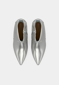 Paari säbriseid hõbedasi terava ninaga pahkluu saapaid, mille esiosas on lukud, vaadatuna ülalt valgel taustal.