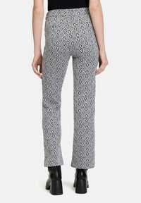 Pantaloni aderenti bianco e nero con motivo geometrico, vita media e svasatura alla caviglia.