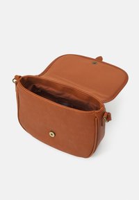Tan læder crossbody taske med magnetisk snaplukning, indvendig lomme og glat overflade. Har en flad form og justerbar rem.