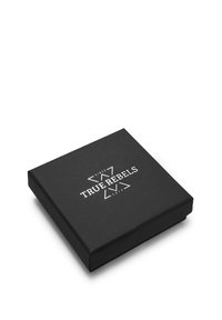 Boîte noire carrée avec une texture matte lisse, présentant un logo imprimé blanc "TRUE REBELS" et l'année "2014" dans un design angulaire.