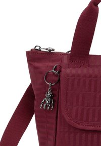 Maroon shoulder bag with textured stripes, featuring a flap closure, a silver zipper, and a metallic charm hanging from the side.
