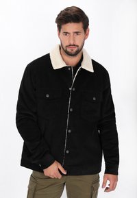 Fekete bordázott dzseki világos szőrmés gallérral, két mellzsebbel és gombos záródással. Texturált anyag, laza fit.