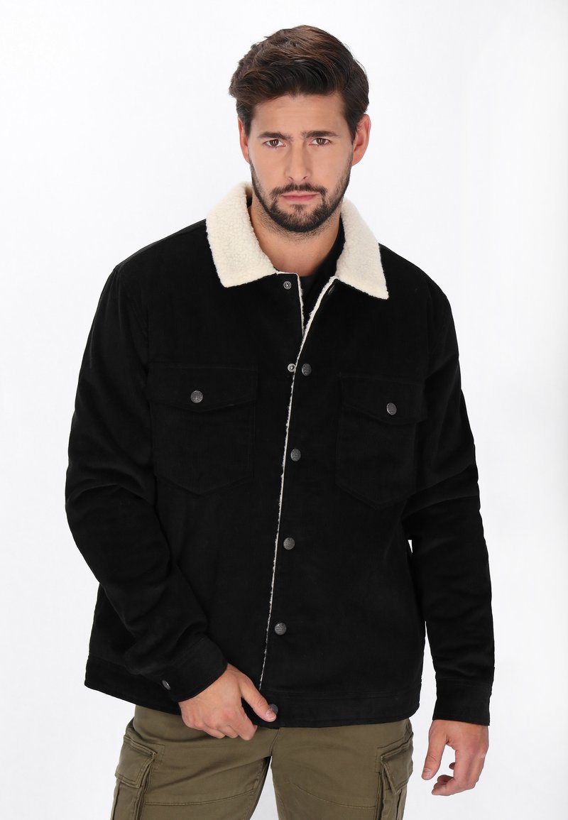 Fekete bordázott dzseki világos szőrmés gallérral, két mellzsebbel és gombos záródással. Texturált anyag, laza fit.
