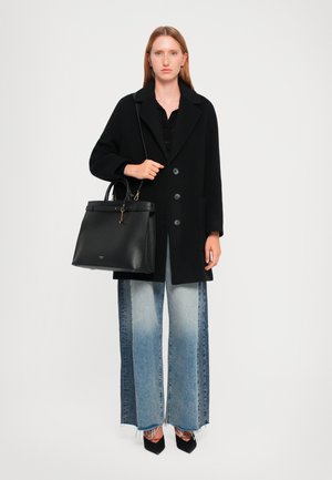 Black wool coat with large buttons, paired with a black structured handbag. Wide light blue denim jeans with a gradient fade and frayed hem.