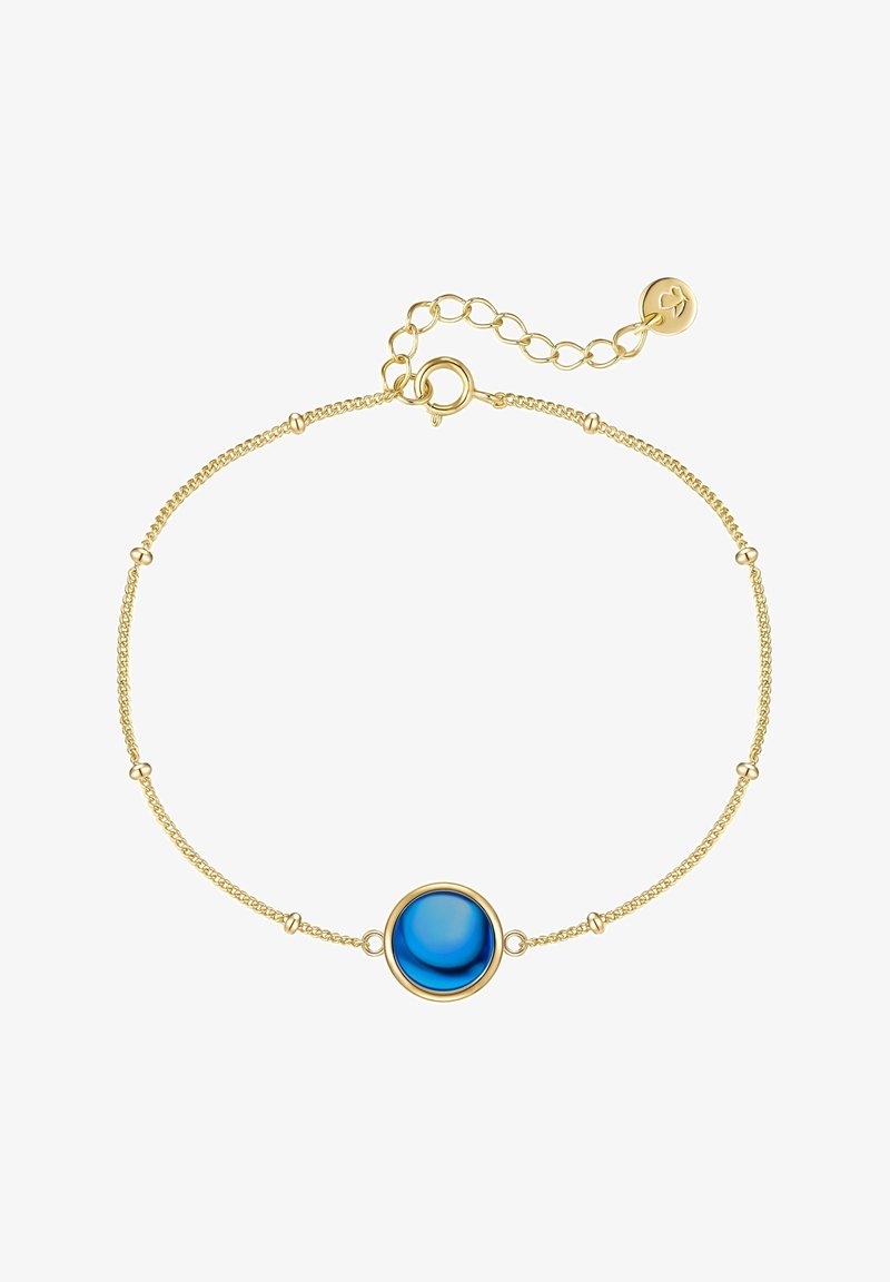 Zlato obarvana zapestnica z osrednjim modrim okroglim kamenjem, zasnovana z občutljivo verigo in majhnimi kovinskimi poudarki. Nastavljiv detajl zaponke.