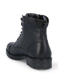 Botín de cuero negro hasta el tobillo con cordones en el frente, cuello acolchado y suela de goma texturizada. Presenta detalles de costura y una cremallera de metal.