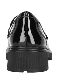 Schwarze Lackleder-Lederschuhe mit dicker, gerippter Plateausohle, sichtbaren Nähten und Quasten, von hinten auf einem weißen Hintergrund betrachtet.