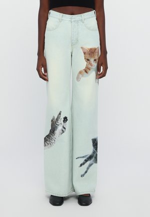 Light blue, oversized denim jeans featuring printed images of jumping cats in various colors, with a straight fit and a high waist.