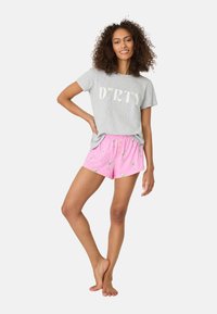 Grå t-shirt med texten "DIRTY" och rosa pyjamasbyxor med mönster av martiniglas. Mjuk tyg, avslappnad passform, elastisk midja på byxorna.