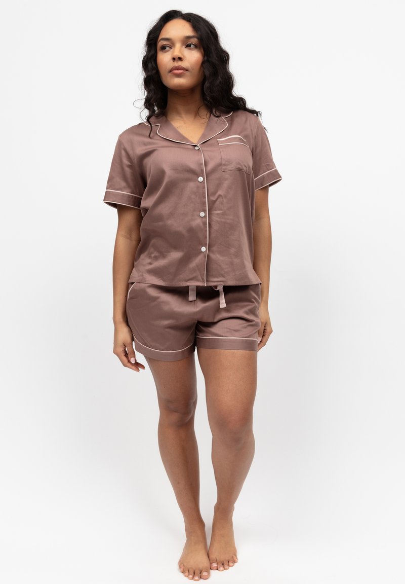 Braunes Satinschlafanzug-Set mit einem kurzärmligen Oberteil mit Tasche und passenden Shorts, beide mit weißen Paspeln entlang der Ränder.
