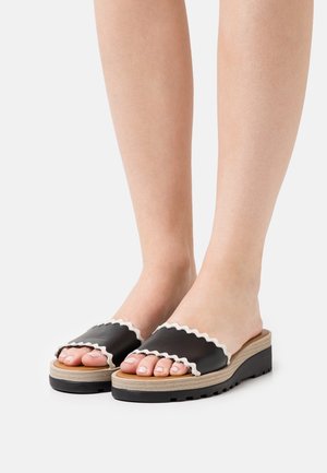 Sandales à glissière noires avec bords festonnés, bride texturée et semelle plateforme marron clair avec une semelle à motif.