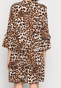 Abito in stampa leopardata con tre strati, maniche corte con dettagli in ruffle, realizzato in tessuto morbido nelle tonalità di marrone e nero.