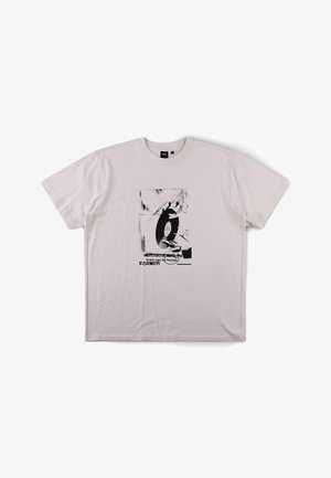 Ανοιχτό γκρι κοντομάνικο μπλουζάκι με ασπρόμαυρο γράφημα ενός χεριού που κρατάει μια βινυλίου δίσκο και κείμενο που λέει "ο εγκέφαλος μπορεί να εξαπατηθεί ΠΡΩΗΝ."