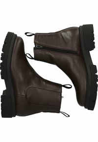 Botas de cuero marrón hasta el tobillo con cierre de cremallera, superficie texturizada y suela gruesa de goma negra. Cuenta con tiradores en la parte posterior para ponerlas y quitarlas fácilmente.