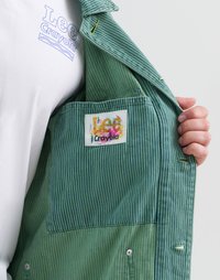 Intérieur d'une veste rayée verte avec une étiquette colorée Lee Crayola, mettant en avant un tissu lisse et des boutons-pression visibles.