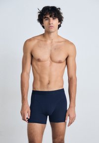 Marineblå boxerbriefs laget av myk stoff med en glatt tekstur og en merkevare-elastisk midje. Har en tettsittende design og middels lengde.