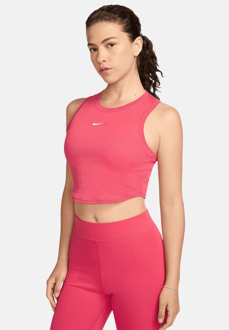 Top corto rosa con texture a coste e scollatura rotonda, con un piccolo logo Nike bianco al centro. Abbinato a pantaloni aderenti rosa coordinati.