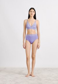 Μπραλέτα από δαντέλα σε λιλά με ρυθμιζόμενους ιμάντες και ταιριαστό ψηλόμεσο εσώρουχο. Με λεία υφή και λεπτομέρειες από ευαίσθητη δαντέλα στη ζώνη.