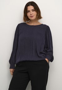 Blusa azul marino de corte relajado, con mangas largas abullonadas, rayas verticales sutiles y un detalle texturizado en los puños.