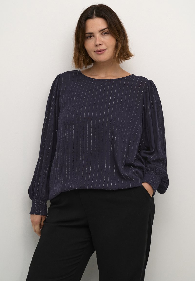 Blusa azul marino de corte relajado, con mangas largas abullonadas, rayas verticales sutiles y un detalle texturizado en los puños.