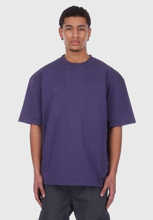 T-shirt en coton violet surdimensionné avec un col rond et des manches courtes. Texture lisse avec un petit logo à l'ourlet.