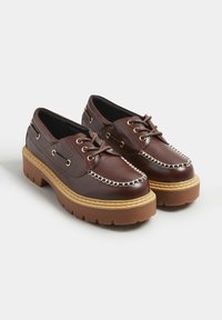 Ruske nahkasaappaat paksulla pohjalla, joissa on ketjusomistuksia, pyöreä kärki ja nauhakiinnitys. Kultaiset yksityiskohdat.