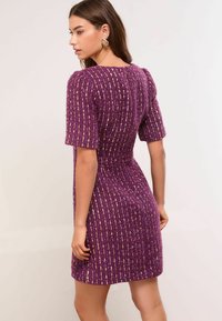 Rochie mov dintr-un material tricotat texturat, cu dungi verticale cu accente de aur. Mâneci scurte și talie fitted cu fustă evazată.