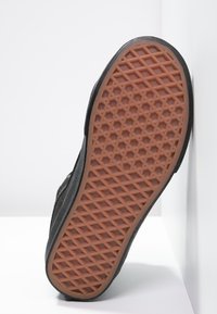 Talpă de sneaker neagră cu un model texturat; material din cauciuc; prezintă un design de prindere hexagonal maroniu și margini netede.