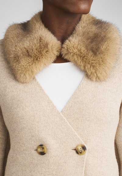 Beige uld cardigan med dobbeltknaplukning, der har en blød faux fur krave i lysebrun og teksturerede knapper.