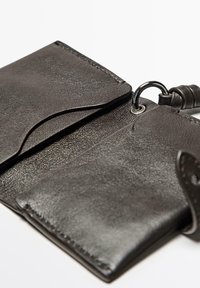 Černá kožená peněženka s texturovaným povrchem. Obsahuje kapsu s klopou, přívěsek na klíče a viditelné prošívání na okrajích.