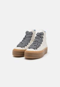 Hoge sneakers van crème canvas, met oversized zwart-witte zigzag veters en een dikke, gemarmerde, doorzichtige rubberen zool.