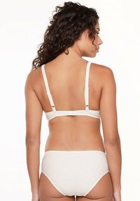 Bikini beige texturé avec des bretelles réglables et une fermeture à crochet. Le bas taille haute présente un motif subtil pour plus de détails.