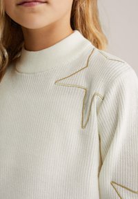 Pulover tricotat de culoare crem, cu guler înalt și broderie cu stele aurii pe umeri. Textură moale cu un model côté.