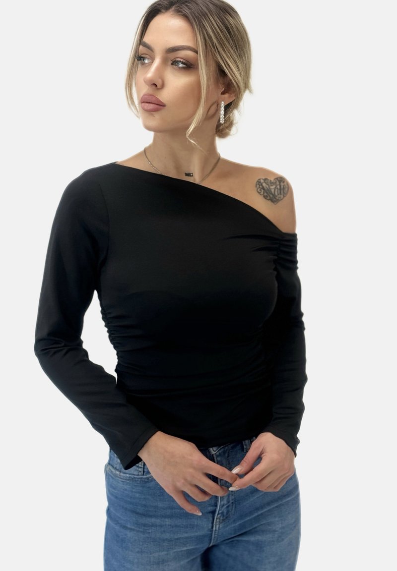 Zwarte longsleeve top met één schouderontwerp, voorzien van een geplooide textuur aan één kant en een gladde stof, gecombineerd met blauwe denim jeans.