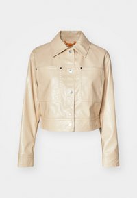 Beżowa skórzana kurtka typu cropped z błyszczącą teksturą, spiczastym kołnierzem, dwoma kieszeniami na piersi oraz ozdobnymi srebrnymi zatrzaskami.