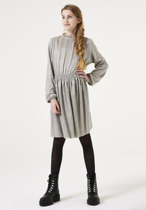 Robe à manches longues en ton argenté, avec un tissu texturé, une taille smockée et une jupe plissée, accompagnée de bottes de combat noires à lacets et de collants.