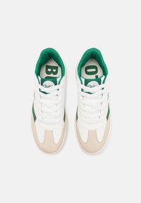 Baskets blanches et vertes avec un bout en suède et des accents latéraux. Présentent un logo rond sur la languette et une doublure intérieure verte perforée.