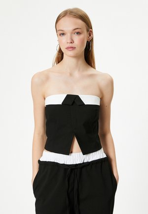 Top negro sin tirantes con banda blanca, con un lazo en la parte frontal y un diseño con abertura. Textura suave, silueta ajustada y forma estructurada.